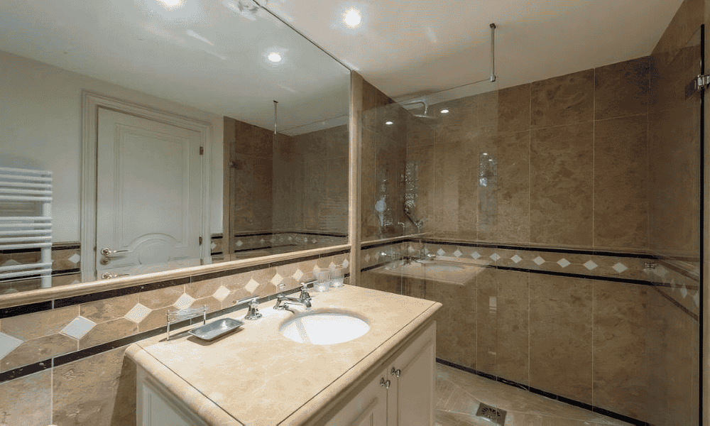 Marble-finished bathroom at Villa Cap d’Antibes featuring a vanity sink, large mirror, and walk-in shower with glass partition
