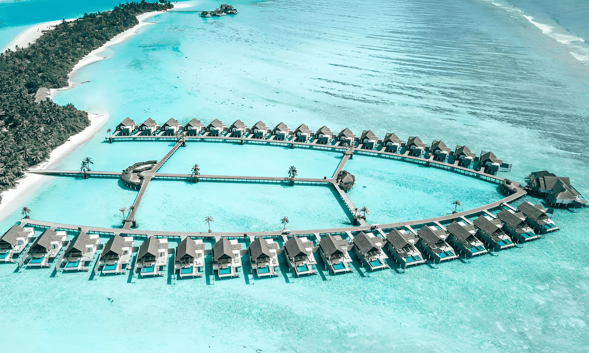 Aerial view of private Villa Hotels buildings in the Maldives, with the ocean in the background.