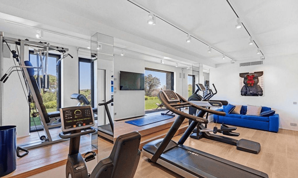Fully equipped gym featuring various exercise machines, including treadmills, weight stations, and cardio equipment in a modern setting.