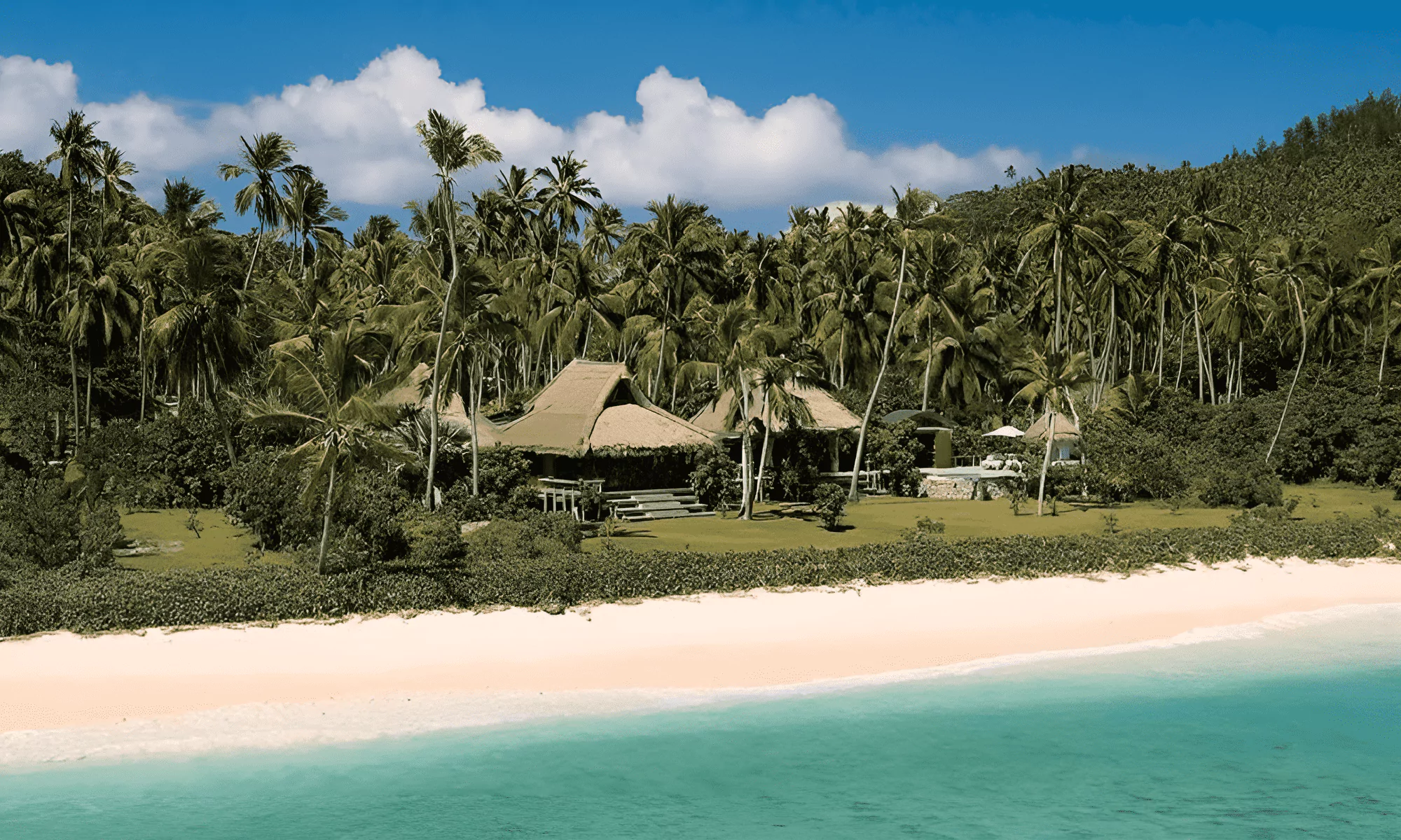 Aerial view of luxury villas surrounded by tropical palm trees.