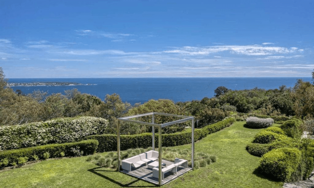 Terrace dining table under pergola overlooking landscaped garden
