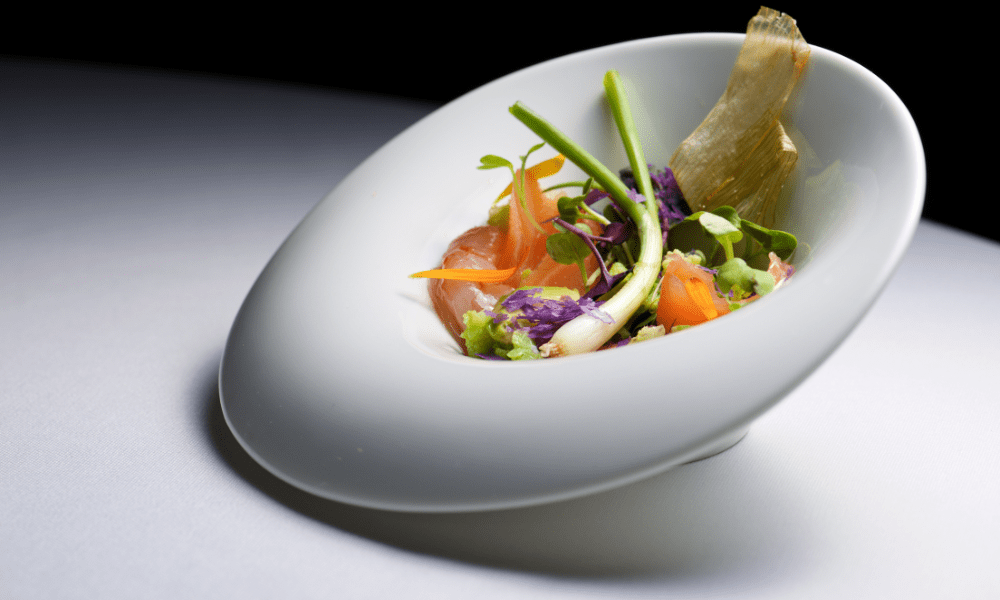 Villa Hotels signature smoked salmon and microgreen salad with pickled carrot curls, vibrant purple cabbage, and a crispy seaweed chip in a white porcelain bowl