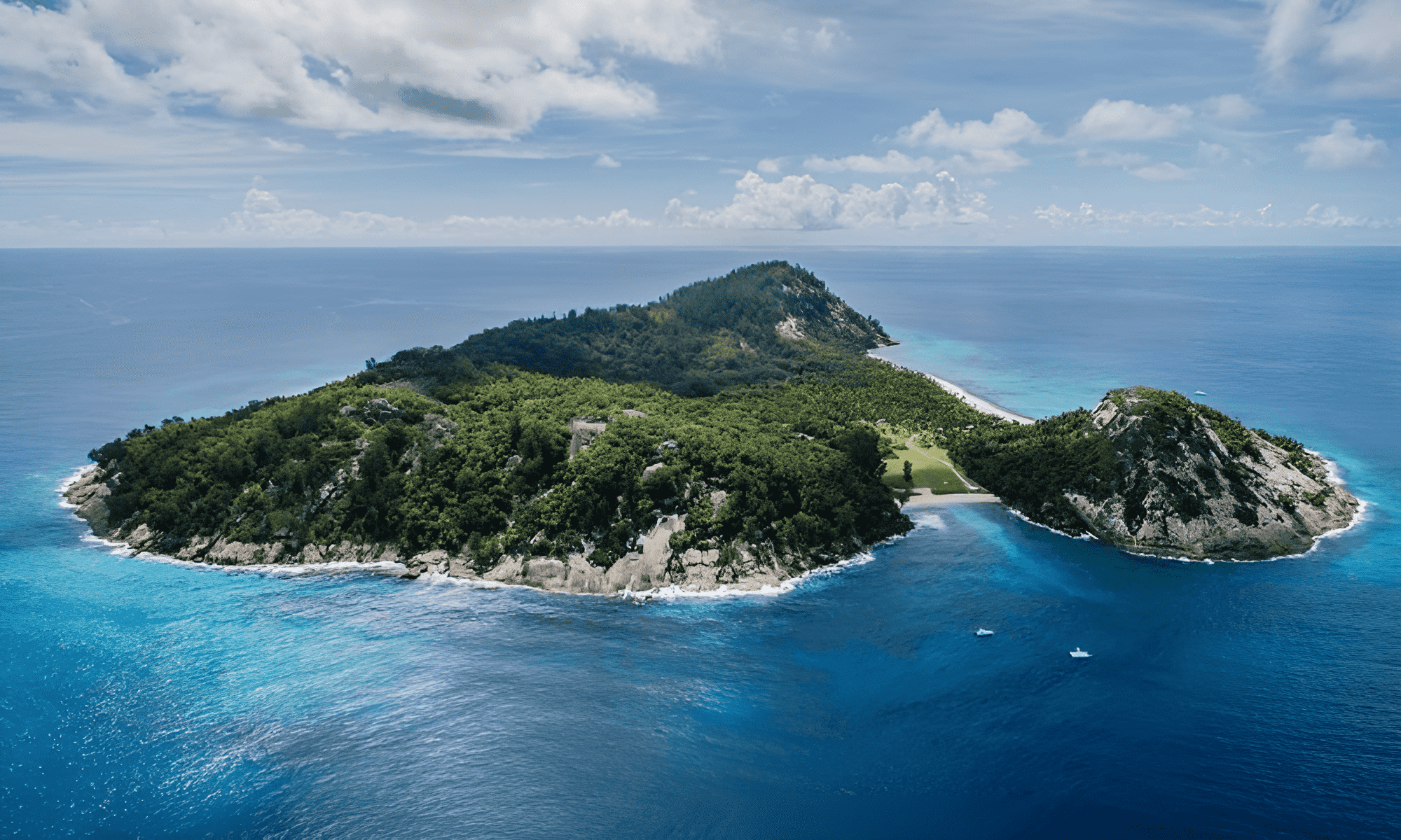 Cliffside villa above a red-rock beach, featuring an infinity pool and lush Mediterranean foliage