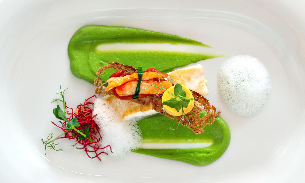 Artfully plated seafood creation with green pea puree, delicate culinary foam, and microgreen accents